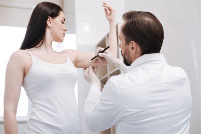 woman preparing for liposuction on her arm with her plastic surgeon