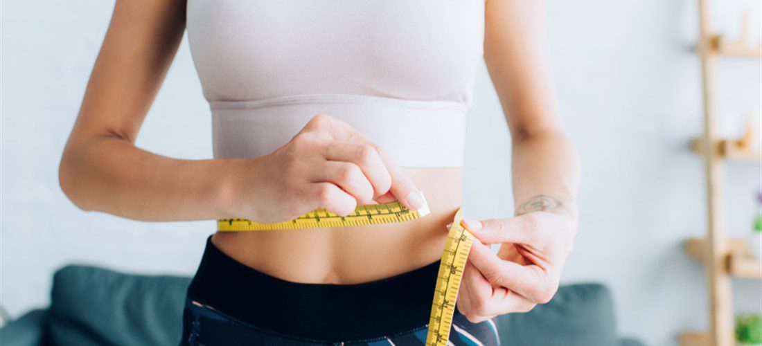 woman measuring her waist reduction after liposuction or coolsculpting procedures